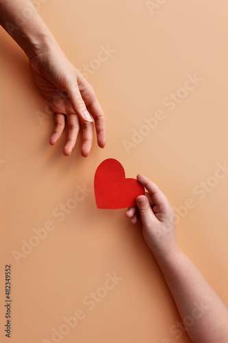 The child holds out a paper heart to the mother. A symbol of children's love