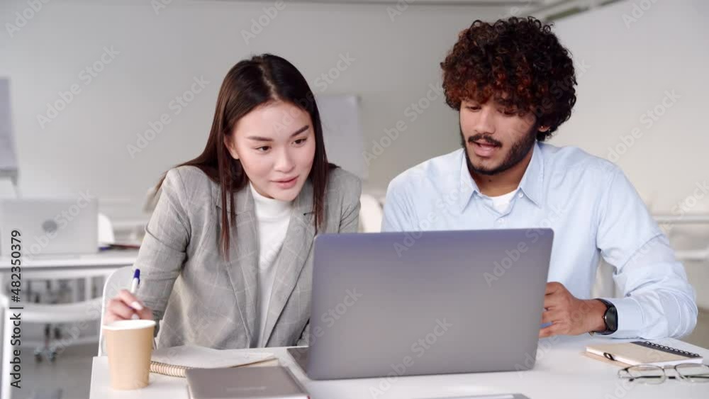 Two creative workers discussing online startup project looking at laptop screen Two creative workers discussing online startup project looking at laptop screen