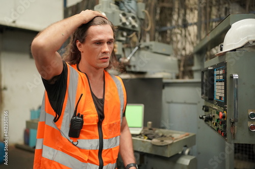 Portrait of Professional Heavy Industry Engineer / Worker Wearing Safety Uniform, Goggles and Hard Hat. In the Background Unfocused Large Industrial Factory