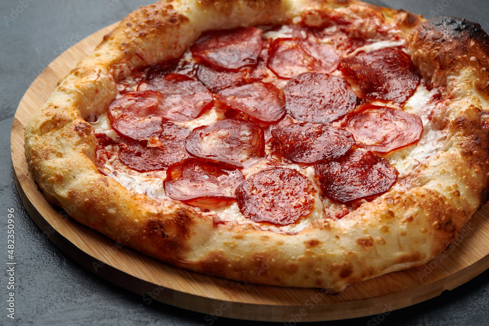 Tasty pepperoni pizza on black concrete background. Top view of hot pepperoni pizza. With copy space for text. Tasty pepperoni pizza on black concrete background. Top view of hot pepperoni pizza. With copy space for text.