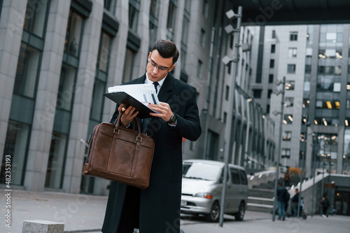 Wallpaper Mural Holding documents. Businessman in black suit and tie is outdoors in the city Torontodigital.ca