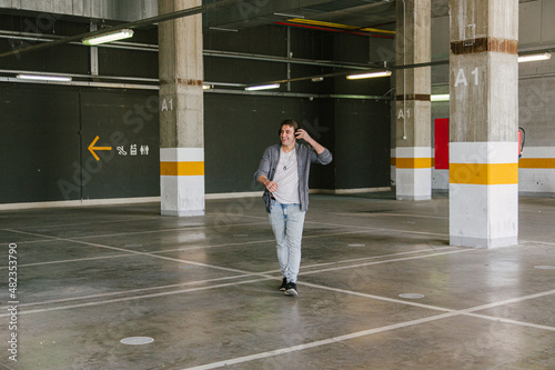 portrait of fashionable cool man on an industrial environment listening to music with earphones. High quality photo