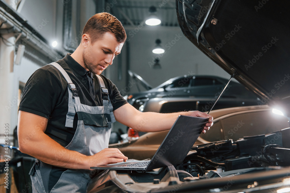 Side view. Man in uniform is working in the auto service Side view. Man in uniform is working in the auto service