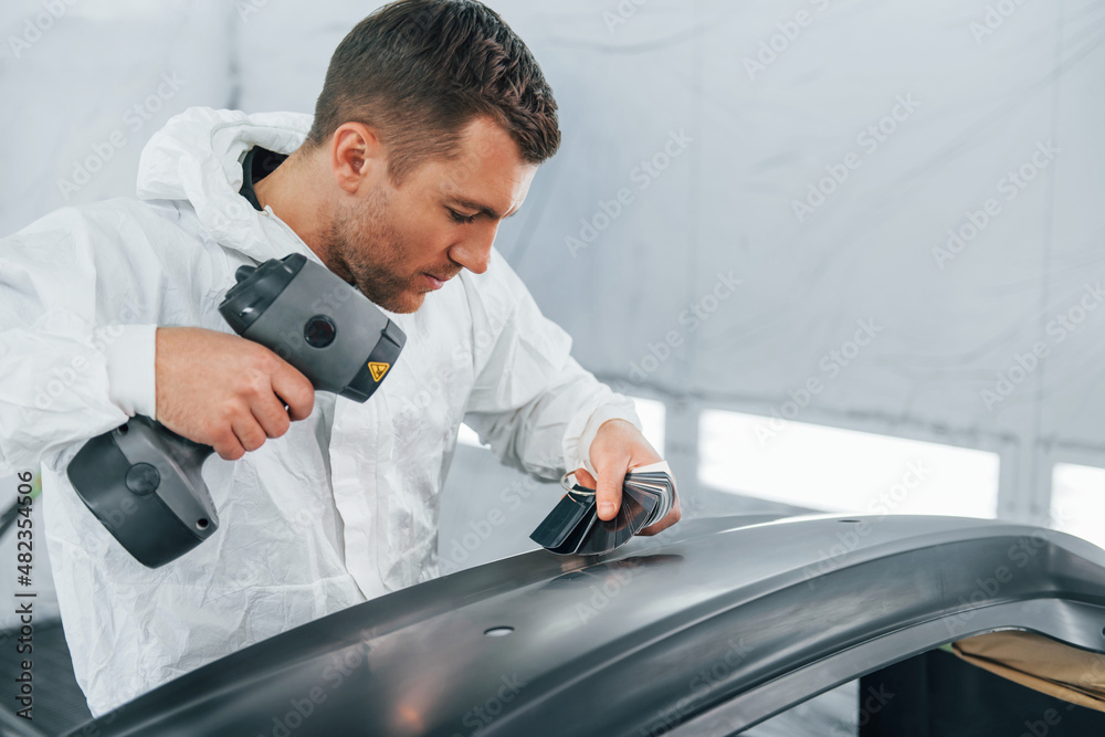 Working with car surface. Man in uniform is working in the auto service Working with car surface. Man in uniform is working in the auto service