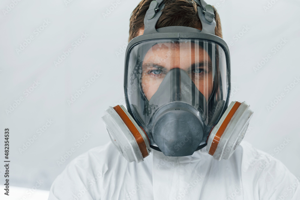 Portrait of man in the protective mask. Worker in uniform is in the auto service