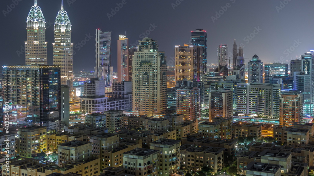 Skyscrapers in Barsha Heights district and low rise buildings in Greens district aerial night timelapse.