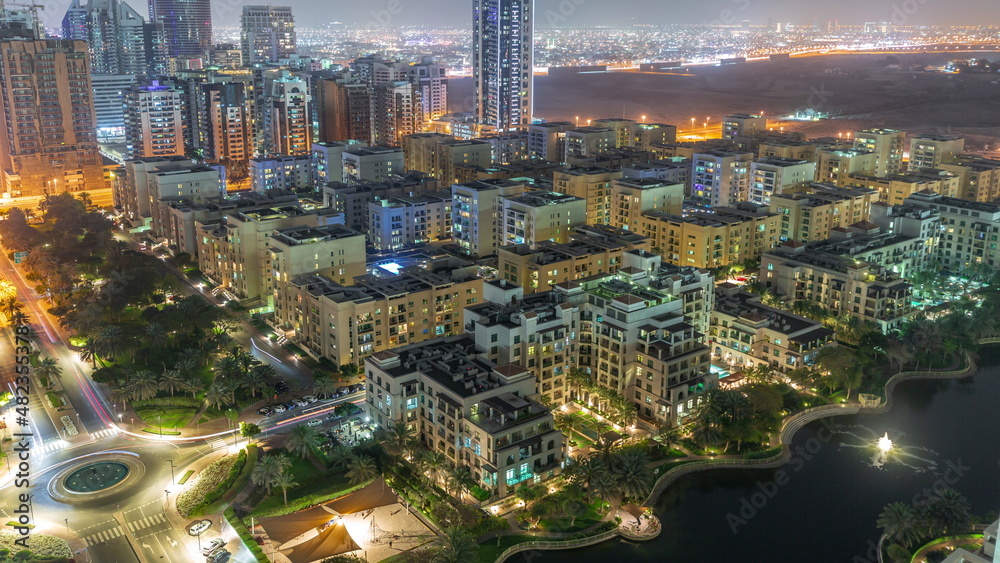 Obraz premium Skyscrapers in Barsha Heights district and low rise buildings in Greens district aerial night timelapse.