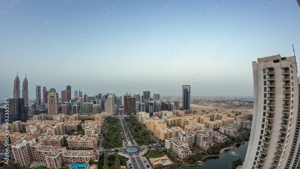 Fototapeta premium Panorama with skyscrapers in Barsha Heights district and low rise buildings in Greens district aerial day to night timelapse.