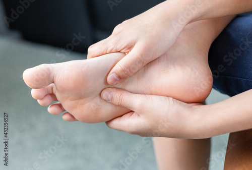 A person holding forefoot with pain, Forefoot pain, metatarsalgia symptom, tenderness in the balls of metatarsal bones in human foot. photo