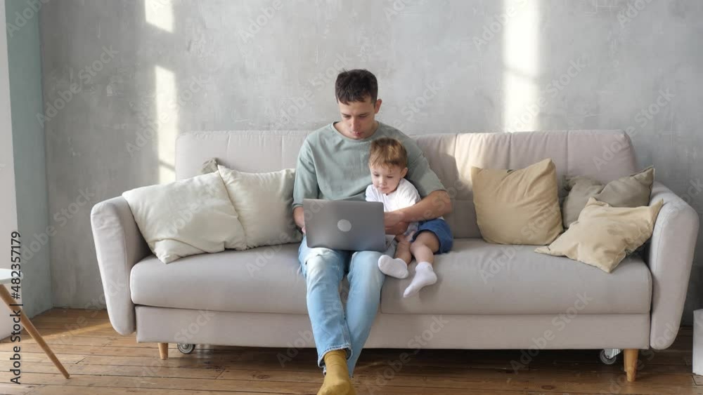 Happy father and cute preschool son using laptop watching cartoon, enjoy watching funny social media videos, online shopping, relaxing together at home on sofa Happy father and cute preschool son using laptop watching cartoon, enjoy watching funny social media videos, online shopping, relaxing together at home on sofa