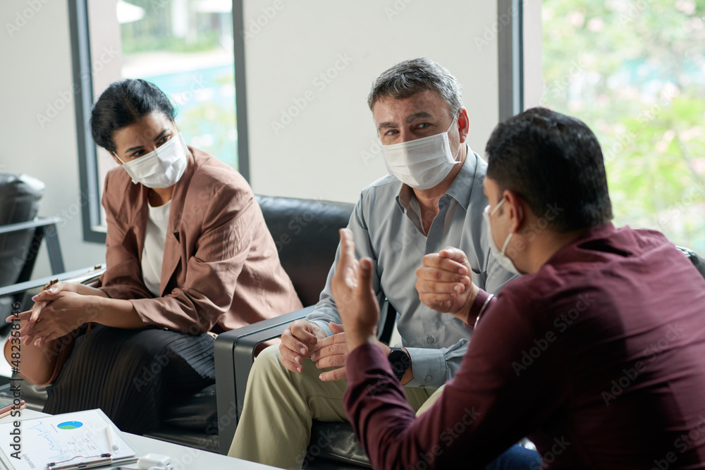 Fototapeta premium Business team in medical masks discussing important issues at meeting in office