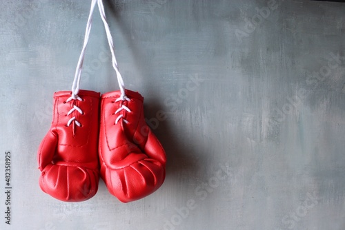 Red boxing gloves hang on wall with copy space for text. Retirement concept © izzuan