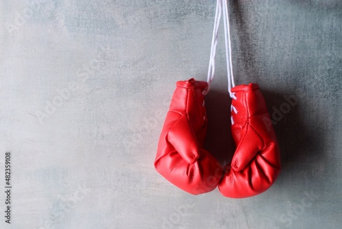 Red boxing gloves hang on wall with copy space for text. Retirement concept © izzuan
