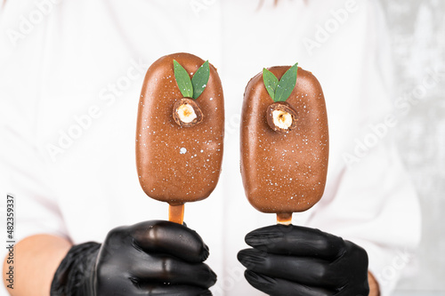 Chocolate cake pops in the form of ice cream on a stick. Confectioner woman holding Iice cream popsicle cake, close up photo