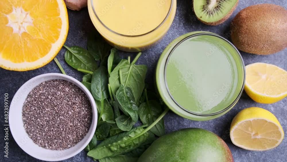 Yellow mango smoothie and green spinach smoothie with ingredients on blue background. Detox drinks concept. Yellow mango smoothie and green spinach smoothie with ingredients on blue background. Detox drinks concept.