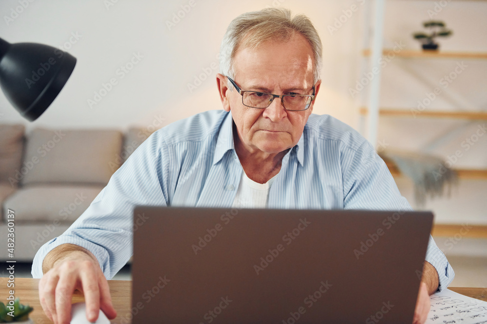 With laptop on table. Senior man in nice clothes is at home With laptop on table. Senior man in nice clothes is at home