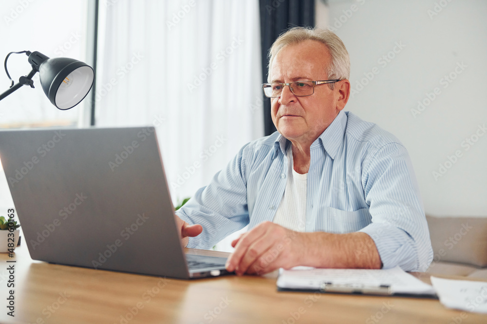 With laptop on table. Senior man in nice clothes is at home With laptop on table. Senior man in nice clothes is at home