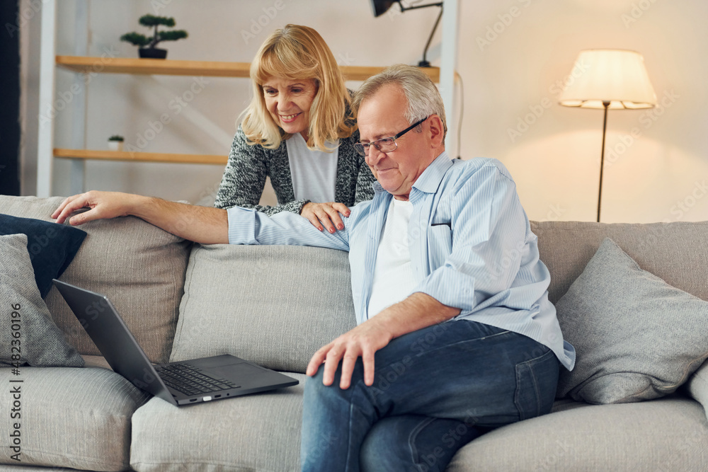 With modern laptop. Senior man and woman is together at home With modern laptop. Senior man and woman is together at home