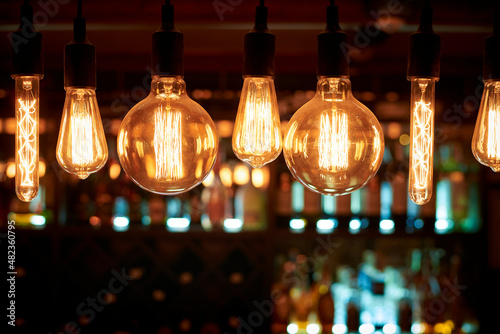 A row of vintage glowing light bulbs on a bar in a restaurant.