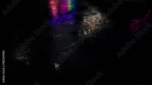 On rainy night, water drops on asphalt. Reflection of neons light