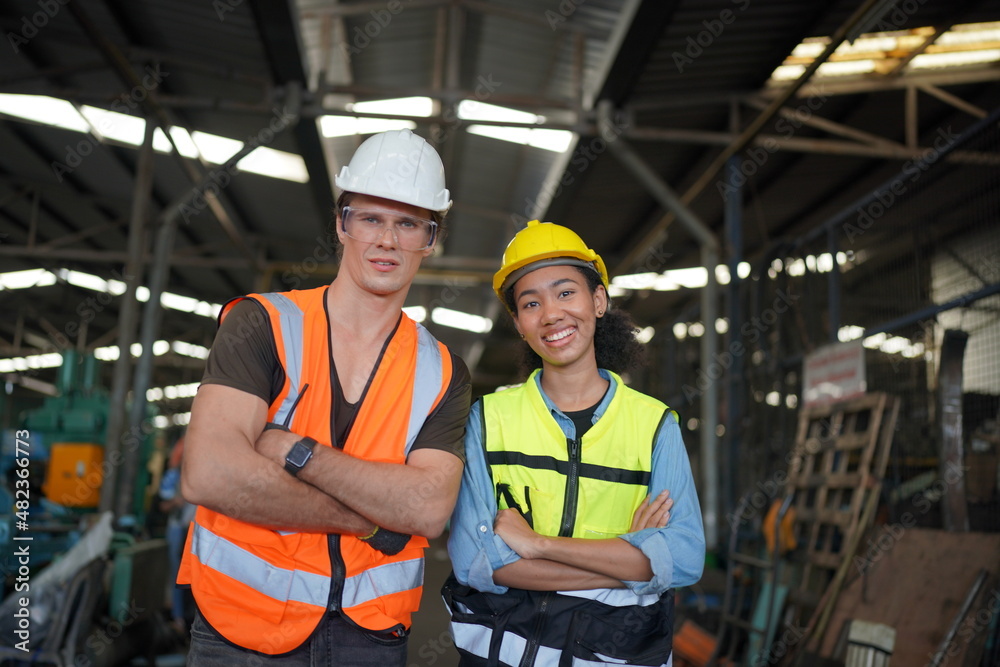 Portrait of male and female engineers working in the metalwork industry. Technical working with lathe machine at factory facility