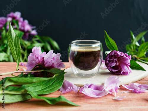 Glass of coffee with pink peonies