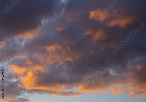 Dramatic sunset evening cloudy sky background in orange, blue and yellow colors. © foxberry