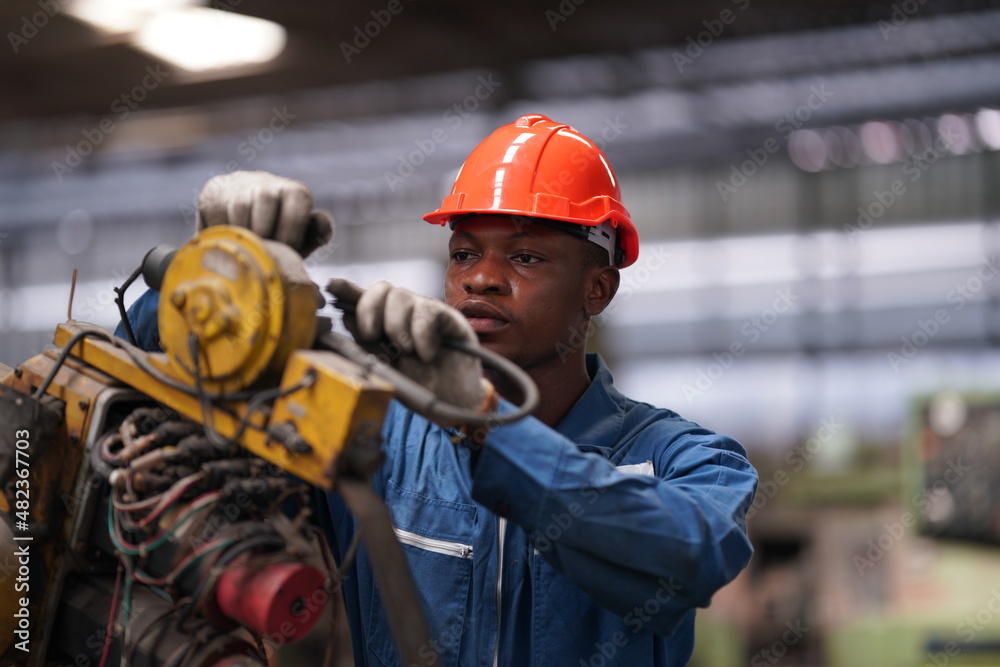 Portrait of Professional Heavy Industry Engineer / Worker Wearing Safety Uniform, Goggles and Hard Hat. In the Background Unfocused Large Industrial Factory Portrait of Professional Heavy Industry Engineer / Worker Wearing Safety Uniform, Goggles and Hard Hat. In the Background Unfocused Large Industrial Factory