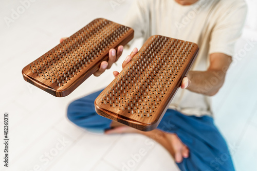 Practice of standing on nails. Man sitting in lotus position with wooden sadhu board with nails for sadhu practice