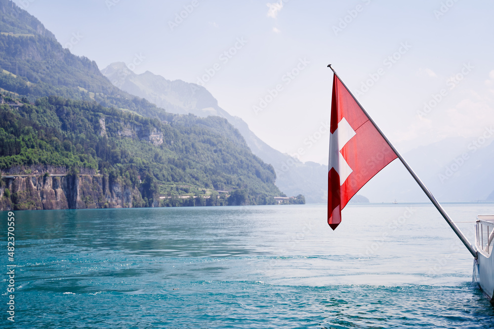 Fototapeta premium National flag of Switzerland with beautiful mountains and lake view.