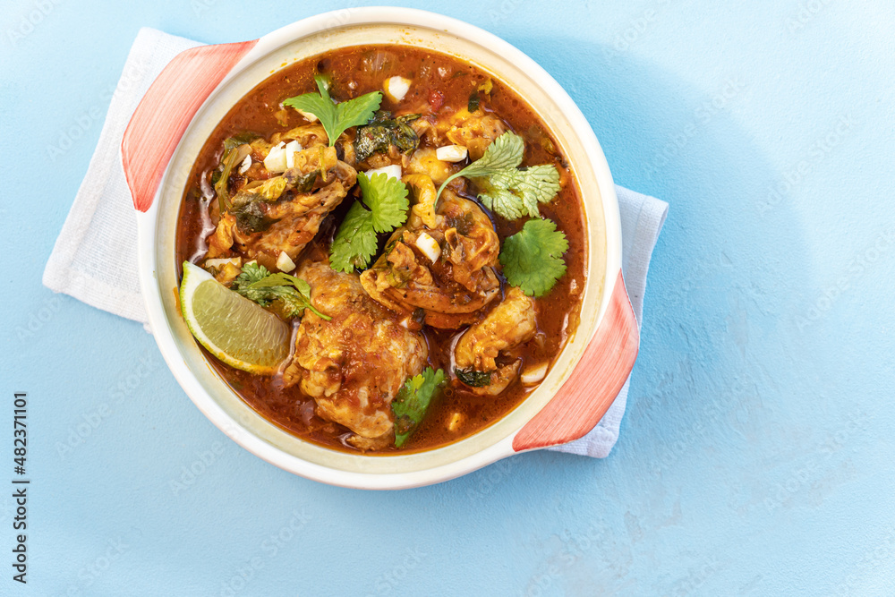 Chicken stewed with tomatoes and vegetables on blue,top view Chicken stewed with tomatoes and vegetables on blue,top view