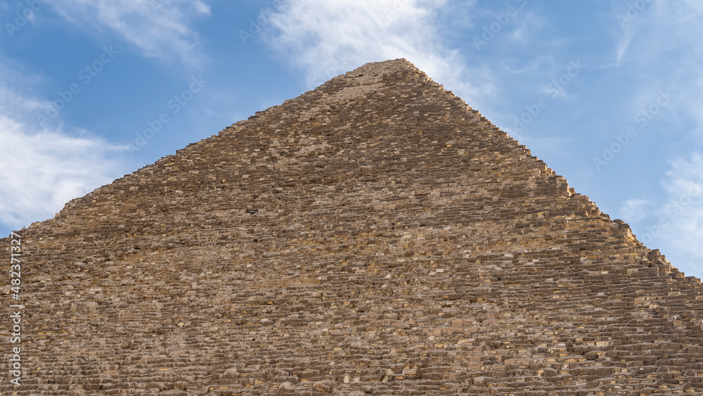 The Great Pyramid of Cheops against the blue sky. The ancient masonry walls are visible. Egypt. Giza