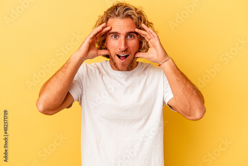 Young caucasian man isolated on yellow background receiving a pleasant surprise, excited and raising hands.