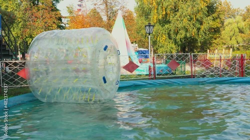 Big plastic bubble on water for children. Zorbing in swimming pool. Favourite children's water activities.