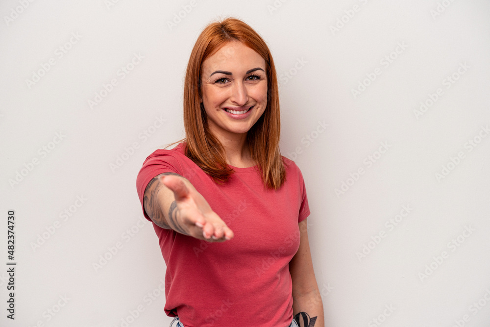 Young caucasian woman isolated on white background stretching hand at camera in greeting gesture. Young caucasian woman isolated on white background stretching hand at camera in greeting gesture.