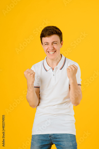 Portrait of a young happy man in white t-shirt smiling and laughing on a yellow