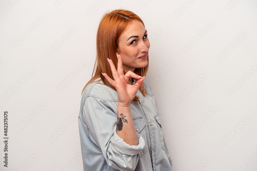 Young caucasian woman isolated on white background winks an eye and holds an okay gesture with hand. Young caucasian woman isolated on white background winks an eye and holds an okay gesture with hand.