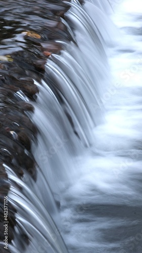 Long exposure on river flowing through rocks in forest, blurred motion.