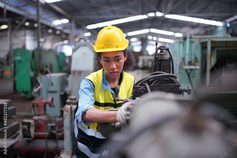 Female apprentice in metal working factory, Portrait of working female industry technical worker or engineer woman working in an industrial manufacturing factory company.