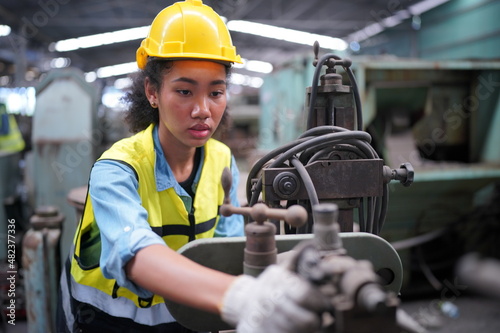 Female apprentice in metal working factory, Portrait of working female industry technical worker or engineer woman working in an industrial manufacturing factory company. © FotoArtist
