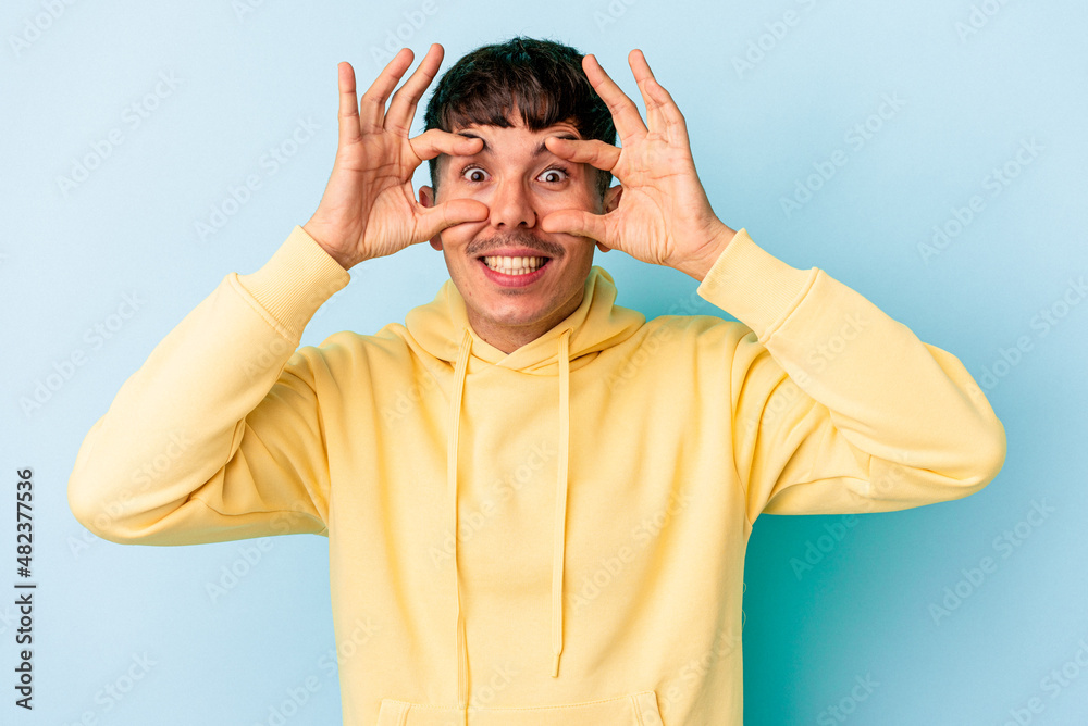 Young mixed race man isolated on blue background keeping eyes opened to find a success opportunity. Young mixed race man isolated on blue background keeping eyes opened to find a success opportunity.