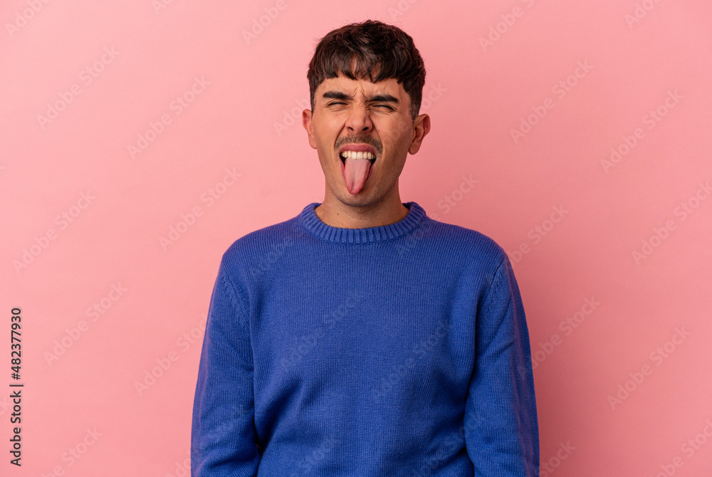 Young mixed race man isolated on pink background funny and friendly sticking out tongue. Young mixed race man isolated on pink background funny and friendly sticking out tongue.
