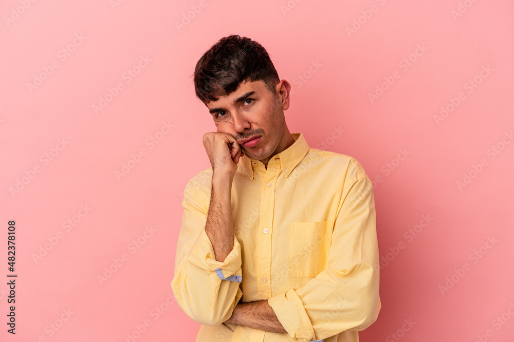 Young mixed race man isolated on pink background tired of a repetitive task.