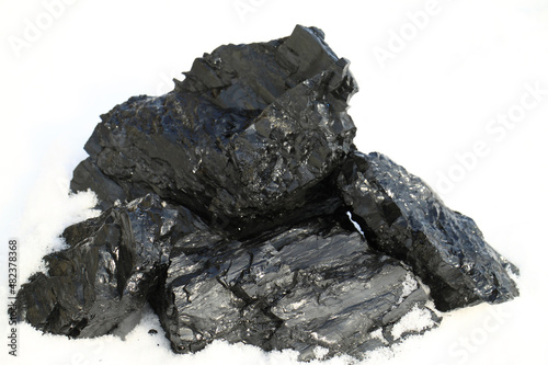 Greater pieces of black coal on a white snow