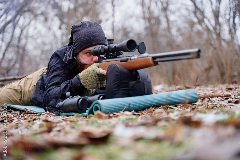 Fototapeta premium Young man aiming at target with the hunting rifle.