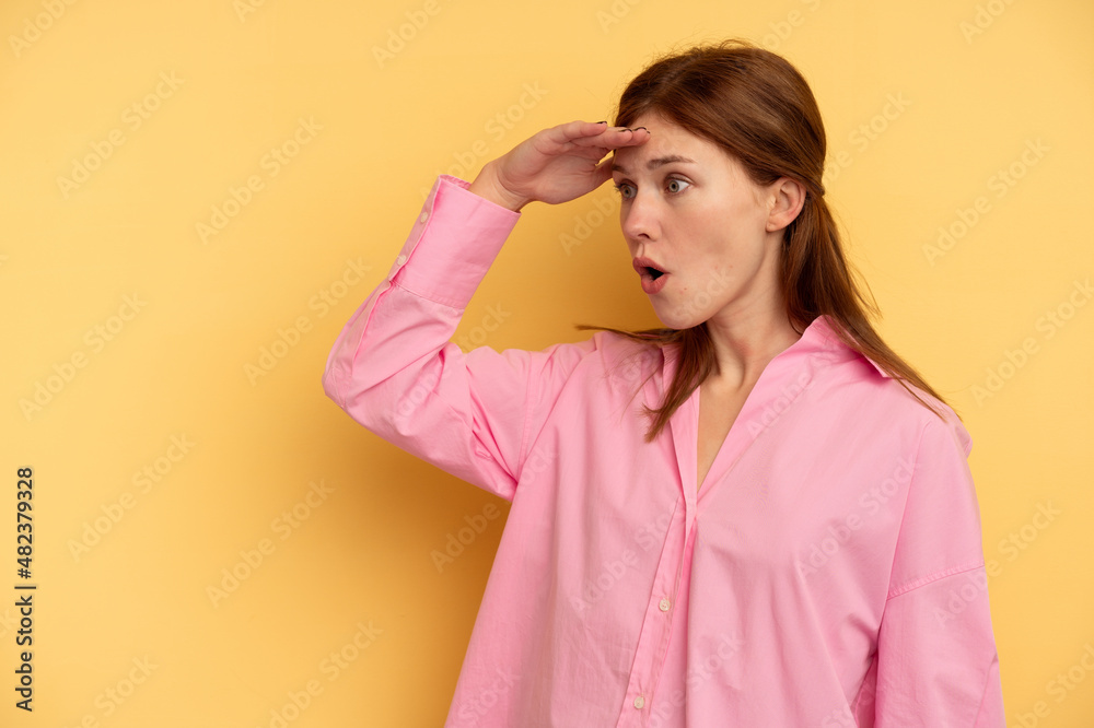 Young English woman isolated on yellow background looking far away keeping hand on forehead.
