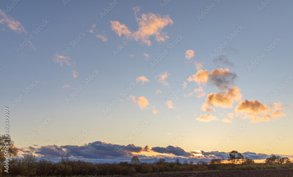 Obraz premium Blue sky with curly clouds and sun, sunset with sun rays.