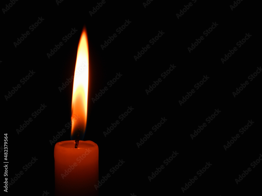Candle flame on black background. Single lit candle with quite flame. Dramatic burning candle flame on a black background with copy space Candle flame on black background. Single lit candle with quite flame. Dramatic burning candle flame on a black background with copy space