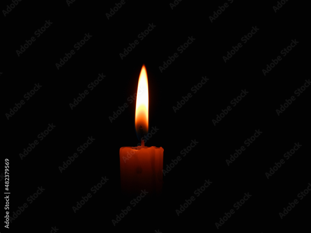 Candle flame on black background. Single lit candle with quite flame. Dramatic burning candle flame on a black background with copy space Candle flame on black background. Single lit candle with quite flame. Dramatic burning candle flame on a black background with copy space