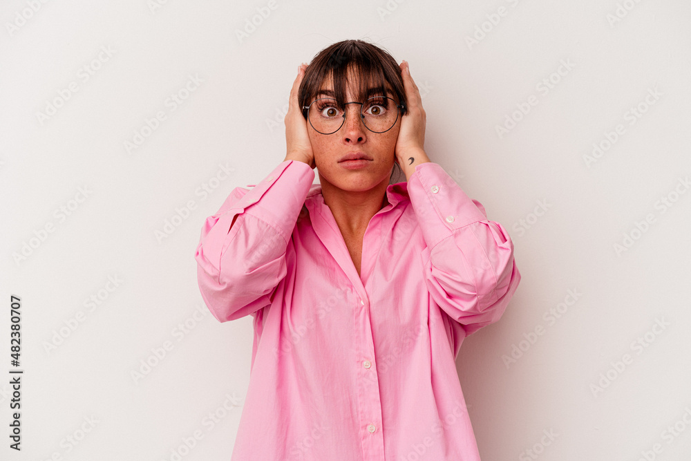 Young Argentinian woman isolated on white background covering ears with hands trying not to hear too loud sound.